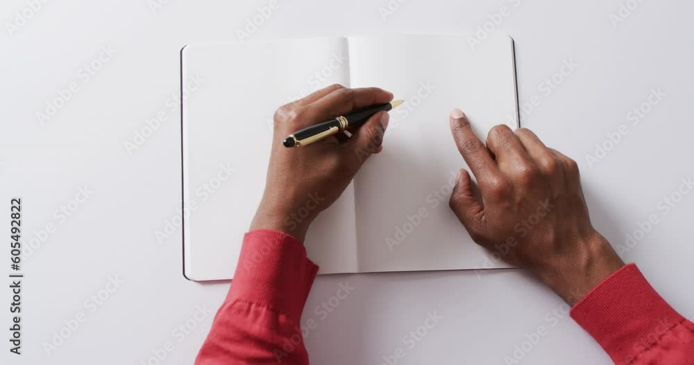 Poster close up of hand writing with pen on book with copy space on white background in slow motion