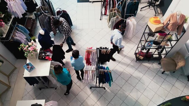 Drone shot Top view of diverse people in modern boutique, shopping for fashionable merchandise and accessories. Stylish customers checking racks full with new fashion collection in clothing store