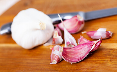 Whole garlic with separated cloves lying on a wooden table. Close-up image..