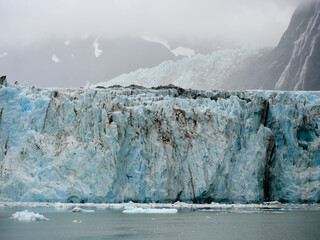 The blue ice on the face of the Surprise Glacier with broken off floes on Prince William Sound near Whittier Alaska in thick mist and fog