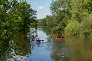 Fototapeta na wymiar Men Paddling Kayaks On The River In Spring