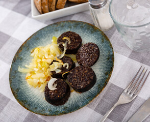 Spanish blood sausage morcilla served with grilled onion on plate