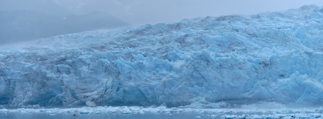 Panoramic image of the blue ice on one of several glaciers with ice floes in the foreground on...