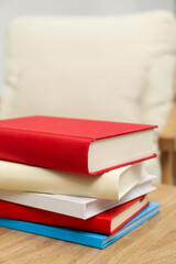 Stack of hardcover books on wooden table indoors, closeup