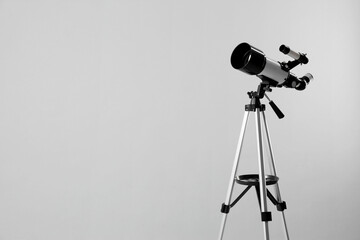 Tripod with modern telescope on light grey background. Space for text