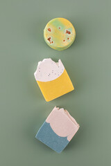 Pieces of different shapes and colors of handmade soap on a green background. Natural cosmetics.