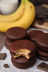 Tasty banana choco pies and pieces of chocolate on parchment paper