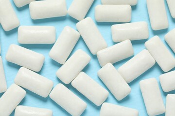 Tasty white chewing gums on light blue background, flat lay