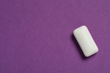Tasty white chewing gum on purple background, top view. Space for text