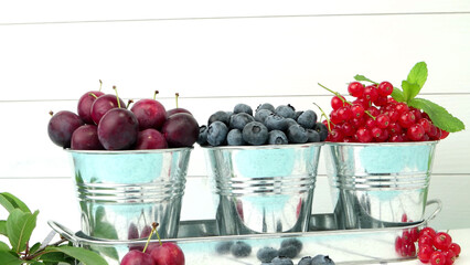 Plums, red currants and blueberries in small metal bucket