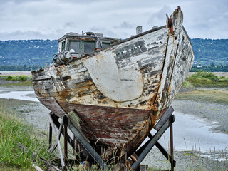Abandoned and rotting sailing vessel at low tide on the Homer spit in Alaska