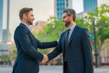 American businessman shaking hands with partner. Business men in suit shaking hands outdoors. Business idea. Business man relationships with client. Handshake between two businessmen.