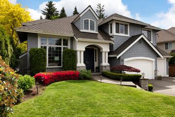 Home exterior with blooming flowers and trees with lush green grass front yard - 605506647