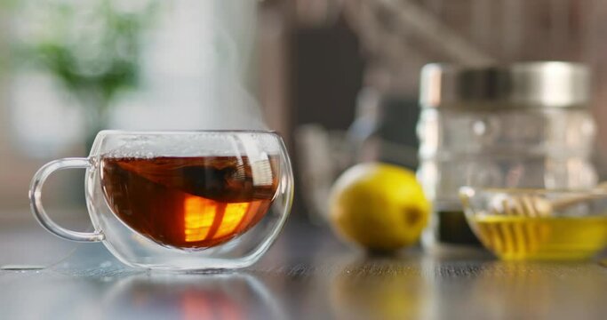 Steaming hot tea cup. Hot tea in glass cup with smoke on wooden table in kitchen