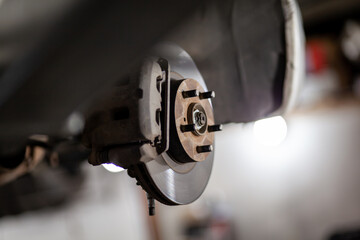 Disc brake of the vehicle for repair, in process of new tire replacement. Car brake repairing in garage.Suspension of car for maintenance brakes and shock absorber systems. Replacement of brake pads.