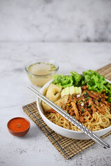 Mie ayam, noodles with chicken and vegetables, Indonesian traditional food in grey texture background.