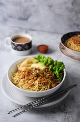 Mie ayam, noodles with chicken and vegetables, Indonesian traditional food in grey texture background.