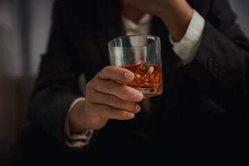 Businessman in black suit holding glass of whiskey Celebrate company success close-up
