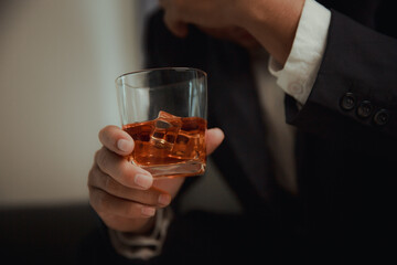 Businessman in black suit holding glass of whiskey Celebrate company success close-up