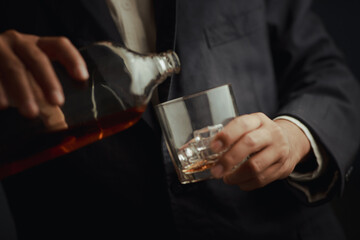 Businessman in black suit holding glass of whiskey Celebrate company success close-up