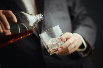 Businessman in black suit holding glass of whiskey Celebrate company success close-up