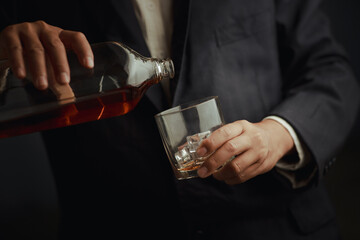 Businessman in black suit holding glass of whiskey Celebrate company success close-up