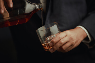 Businessman in black suit holding glass of whiskey Celebrate company success close-up