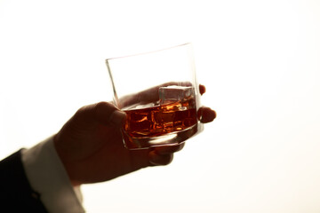 Businessman in black suit holding glass of whiskey Celebrate company success close-up