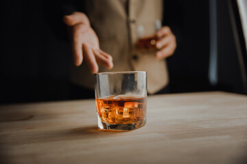 Bartender serving whiskey on wooden bar ,Close-up shot of whiskey glass