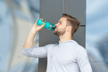 photo of thirsty sportsman drinking water from bottle after training. thirsty sportsman with water