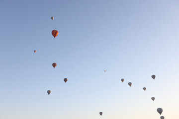 Multi-colored balloons floating up in air against blue sky