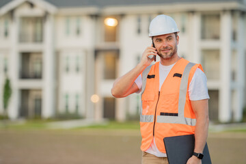 Builder using phone. Builder at construction site. Buider with helmet on construction outdoor. Worker at construction site. Bilder in hardhat.