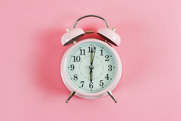 flat lay of pink vintage alarm clock shows 6 o'clock  on pink background with copy space.