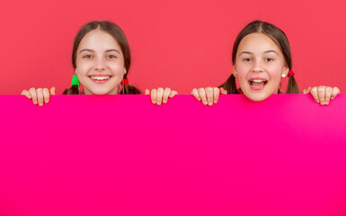 cheerful children behind blank pink paper with copy space for advertisement