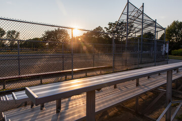 vue sur un terrain de baseball clôturé avec du sable au milieu lors d'un coucher de soleil