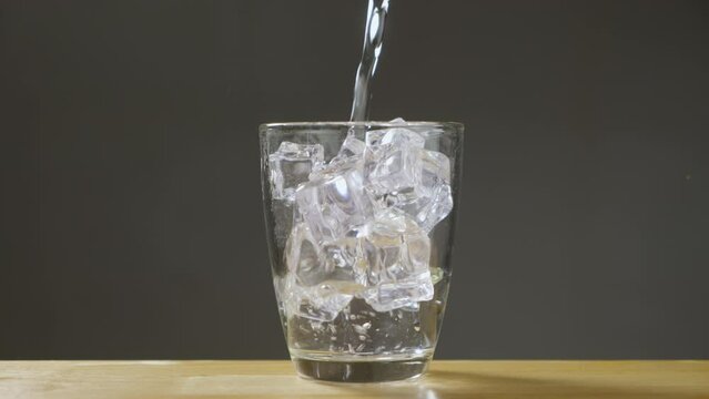 Shoot of water pouring into transparent glass with ice on Table with clear background. Drinking water is pouring into the glass that have ice in the glass. B Roll slow motion 4k.