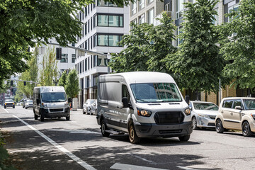Commercial cargo mini vans making deliveries driving on the urban city street with multilevel apartment buildings © vit