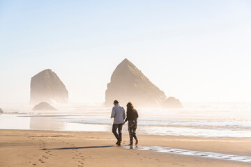 Couple of man and woman walk along the coast in the Pacific Northwest in the rays of the sun soluble in mist spray © vit