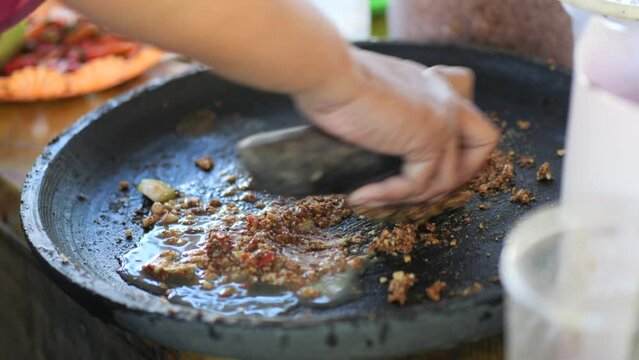 Preparing rujak petis.Rujak petis is traditional food from Java made from steamed mix vegetables, black sauce made from fried garlic, chillies, petis (black fermented shrimp paste) and ground peanuts
