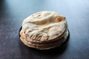 Freshly baked arabic or Pakistani flat bread Kuboos or roti on a black background. Kuboos or khubz...
