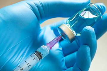 doctor's hand holds a syringe and a blue vaccine bottle at the hospital. Health and medical...