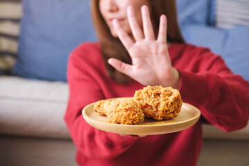 Closeup of a woman making hand sign to refuse fried chicken for dieting and healthy eating concept