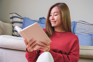 Obraz premium Portrait image of a young woman reading a book at home