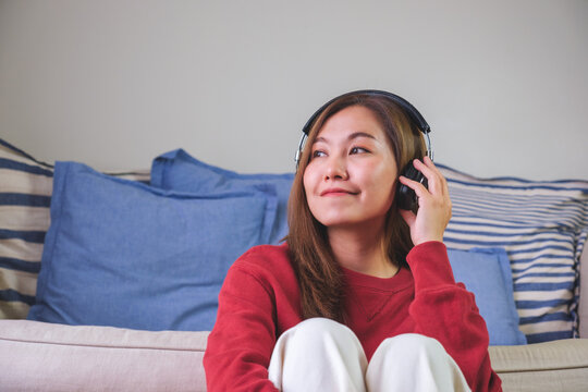 Portrait image of a beautiful young asian woman enjoy listening to music with headphone at home