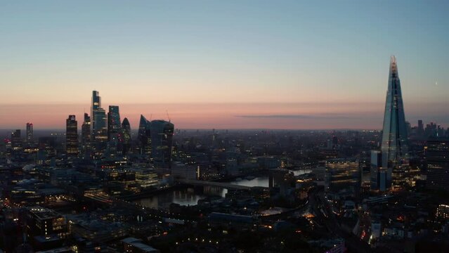 Slow dolly back aerial shot of central London skyscrapers at dawn