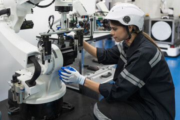 Female engineer control autonomous mobile robot or AMR in the manufacturing automation and robotics room. Female engineer inspecting quality of robotics arm