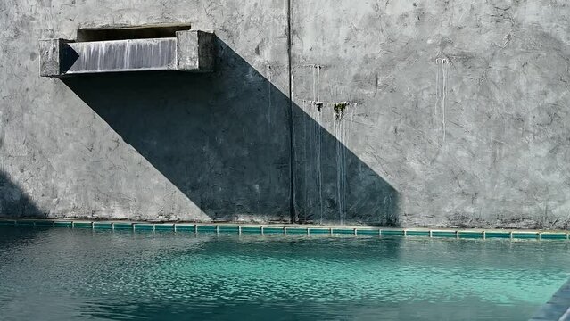 water wave slow motion with faucet of swimming pool on cement wall, construction industry
