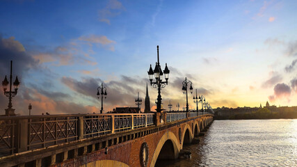 Panorama view in sunset sky scene of the Pont de pierre at sunset in the famous winery region Bordeaux, France. - obrazy, fototapety, plakaty