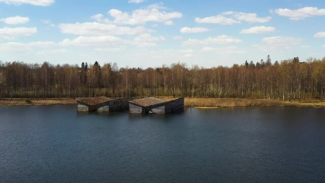 Old grunge boat garages on a lake for boat parking, aerial dolly in
