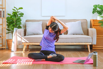 Young Asian healthy woman exercising with laptop at home